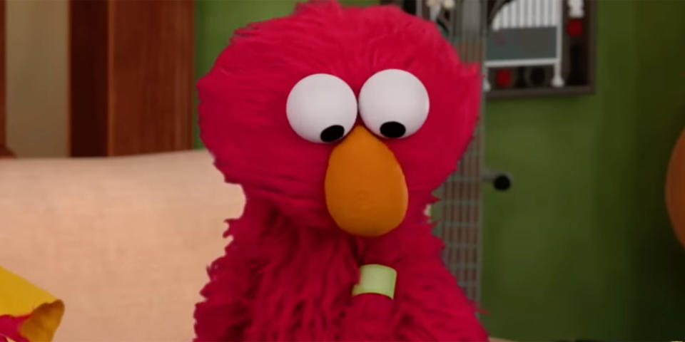 Elmo checks out his brand-new bandage after getting a COVID-19 vaccine. (Sesame Street Workshop)