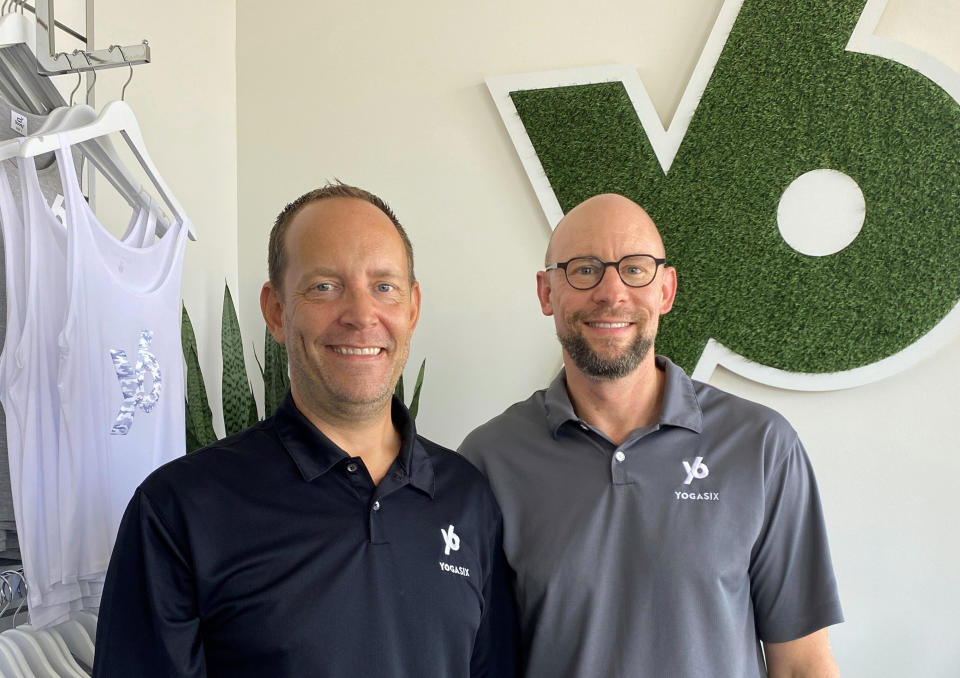 This photo provided by YogaSix La Quinta shows Chris Dordell and Jason Fenske on July 27, 2022 in Palm Springs, Calif. When Chris Dordell and his husband Jason Fenske decided to leave their jobs at Wells Fargo and Salesforce and open two Club Pilates in 2018 and a YogaSix studio in 2020, in and around Palm Springs, they appreciated the playbook provided by the franchisor, Xponential. “It was appealing at this stage after being in corporate jobs for 20-plus years that we could plug into an existing model,” Dordell said. (YogaSix La Quinta via AP)