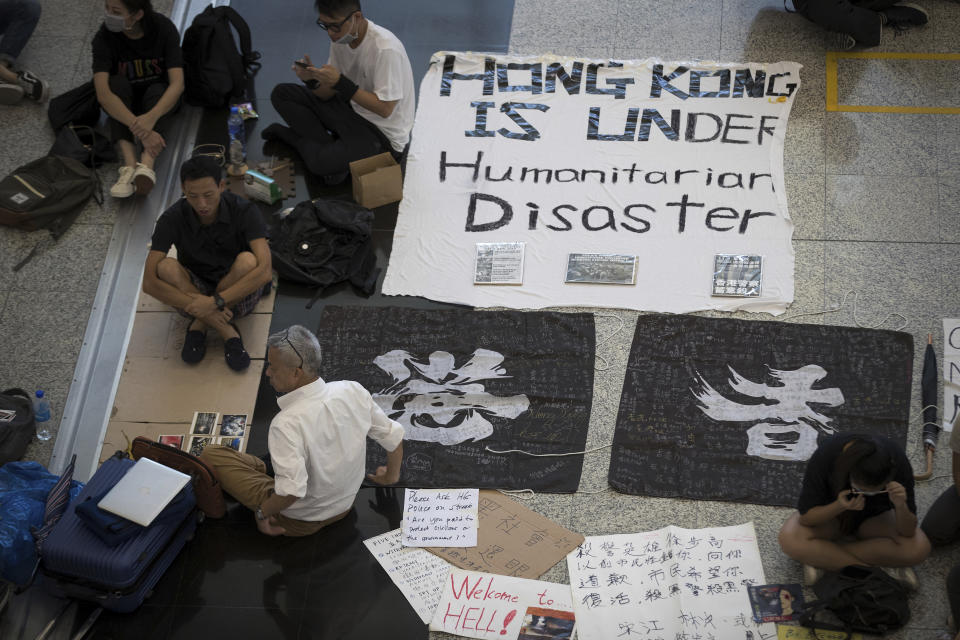 A traveler, bottom left, sits with protesters during a sit-in rally at the Hong Kong International Airport in Hong Kong, Tuesday, Aug. 13, 2019. (Photo: Vincent Thian/AP)