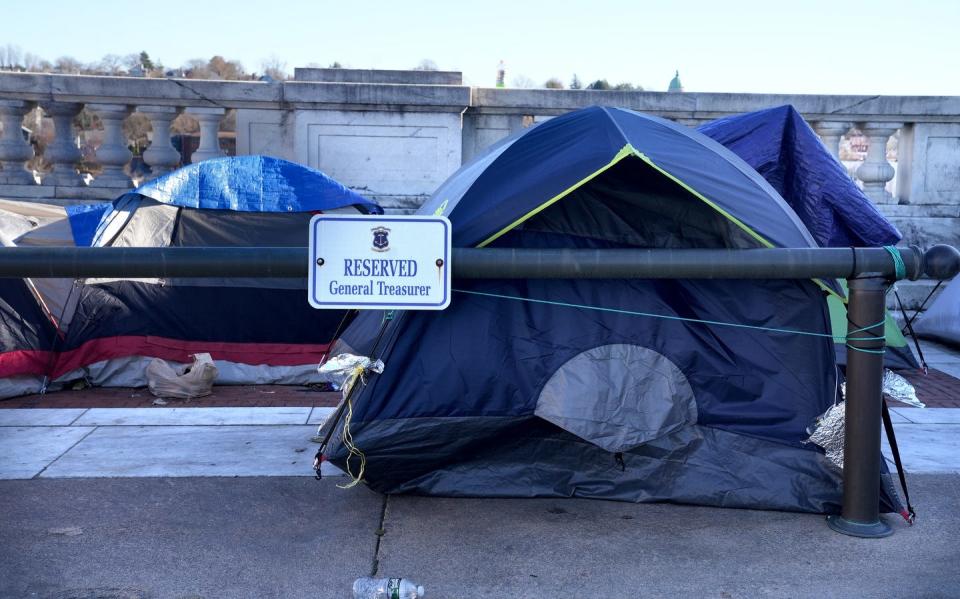 A tent remains Friday as part of the encampment by the homeless at the State House after a judge issued a temporary restraining order.