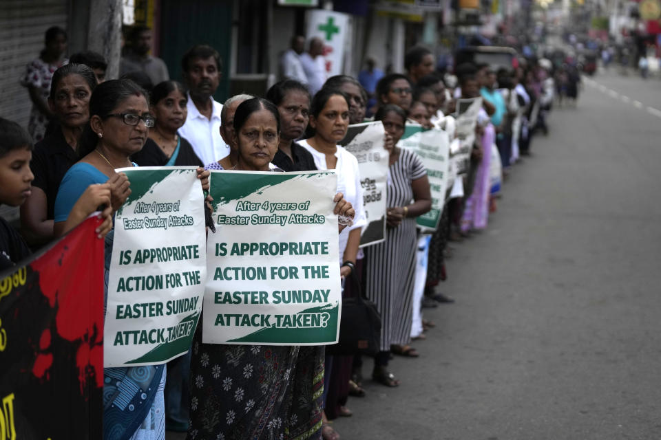 Sri Lankan Catholics hold banners standing on the side of a road during a silent march to mark the fourth year commemoration of the 2019, Easter Sunday bomb attacks on Catholic Churches, in Colombo, Sri Lanka, Friday, April 21, 2023. Thousands of Sri Lankans held a protest in the capital on Friday, demanding justice for the victims of the 2019 Easter Sunday bomb attacks that killed nearly 270 people. (AP Photo/Eranga Jayawardena)