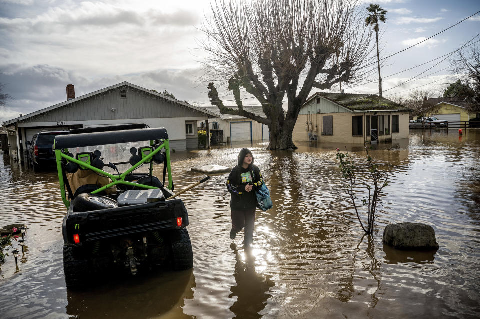 Brenda Ortega, 15, salvages items from her flooded Merced, Calif., home on Tuesday, Jan. 10, 2023. Following days of rain, Bear Creek overflowed its banks leaving dozens of homes and vehicles surrounded by floodwaters. (AP Photo/Noah Berger)