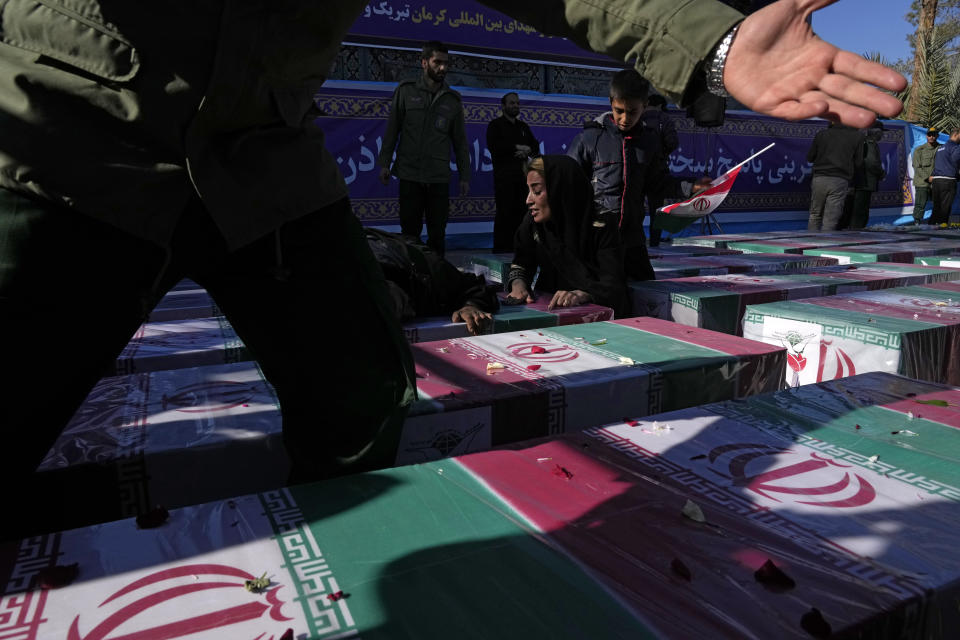 A woman mourns over the flag-draped coffin of her loved one who was killed in Wednesday's bomb explosion, during the victims funeral ceremony in the city of Kerman about 510 miles (820 kms) southeast of the capital Tehran, Iran, Friday, Jan. 5, 2024. Iran on Friday mourned those slain in an Islamic State group-claimed suicide bombing targeting a commemoration for a general slain in a U.S. drone strike in 2020, as the death toll in the attack rose to at least 89. (AP Photo/Vahid Salemi)