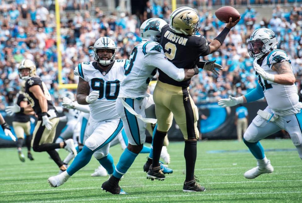 Panthers defensive end Brian Burns, center, wraps his arms around Saints quarterback James Winston during the game at Bank of America Stadium on Sunday. The Panthers defeated the Saints 26-7.