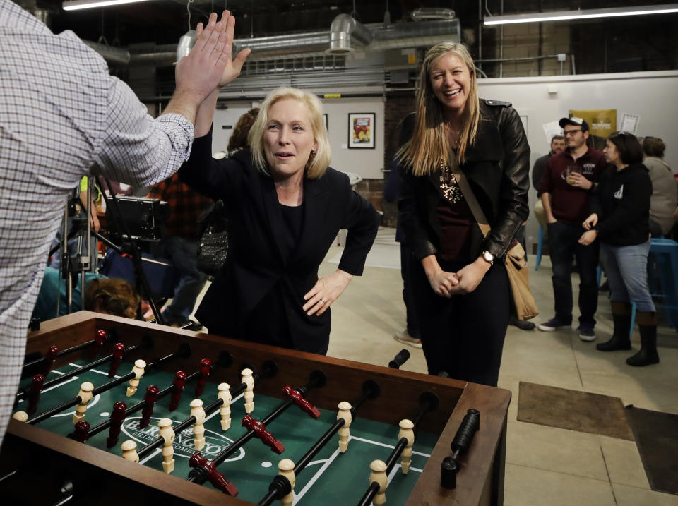 Democratic presidential candidate Sen. Kirsten Gillibrand, D-N.Y., high-fives a foosball opponent as partner Casey Leach of Manchester, N.H., laughs at a campaign meet-and-greet, Friday, March 15, 2019, at To Share Brewing in Manchester, N.H. (AP Photo/Elise Amendola)