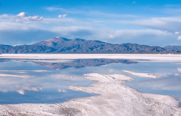 A lithium brine pool with mountain and blue sky in background.