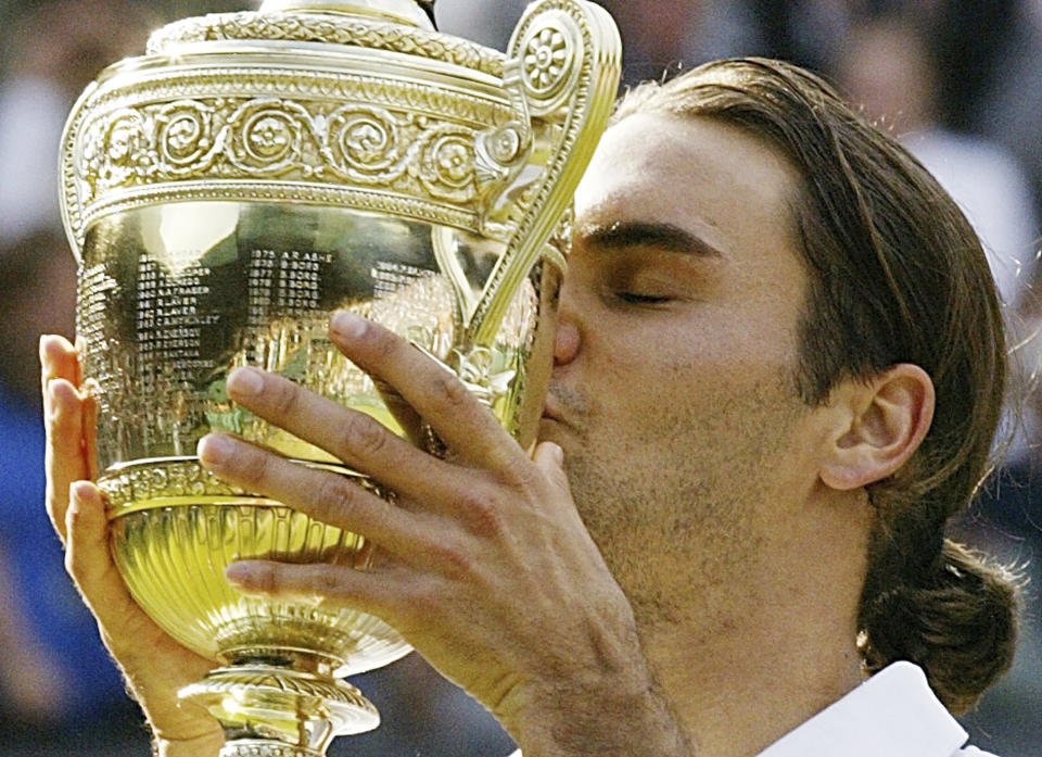 FILE - Roger Federer kisses the winner's trophy after winning the Men's Singles final on the Centre Court at Wimbledon, Sunday July 4, 2004. Federer won the match 4-6, 7-5, 7-6 (3), 6-4, to retain the title. Federer announced Thursday, Sept.15, 2022 he is retiring from tennis.(AP Photo/Anja Niedringhaus, File)