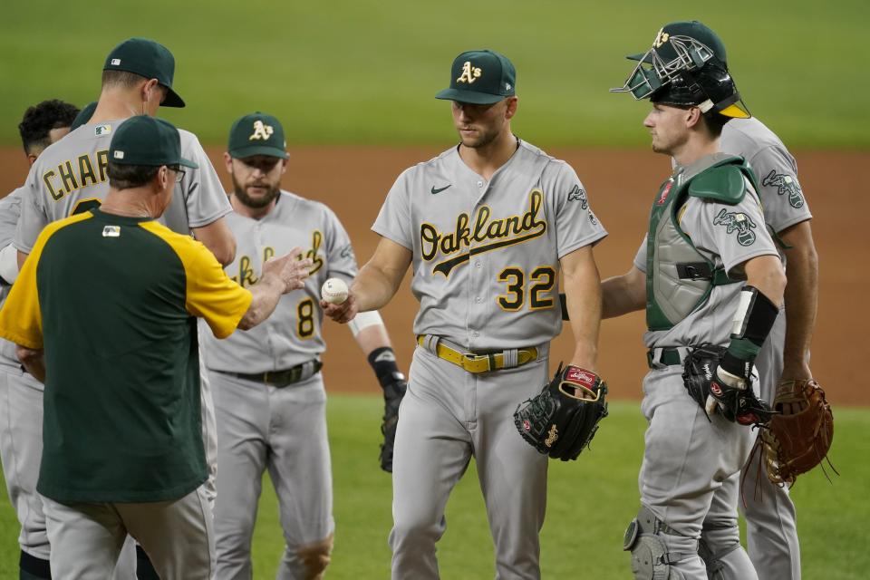 Oakland Athletics manager Bob Melvin, front left, takes the ball from starting pitcher James Kaprielian (32) as Jed Lowrie (8), Sean Murphy, right, and the rest of the infield stand by in the sixth inning of the team's baseball game against the Texas Rangers in Arlington, Texas, Saturday, Aug. 14, 2021. (AP Photo/Tony Gutierrez)