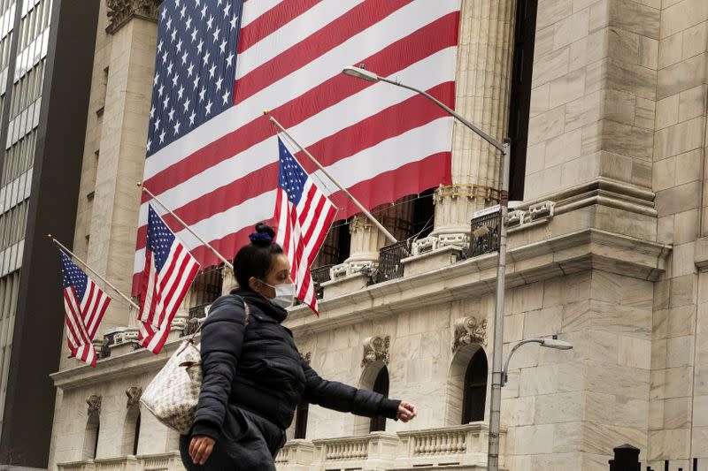 FILE PHOTO: A pedestrian with a mask walks past of the NYSE as markets continue to react to the coronavirus disease (COVID-19) at the NYSE in New York