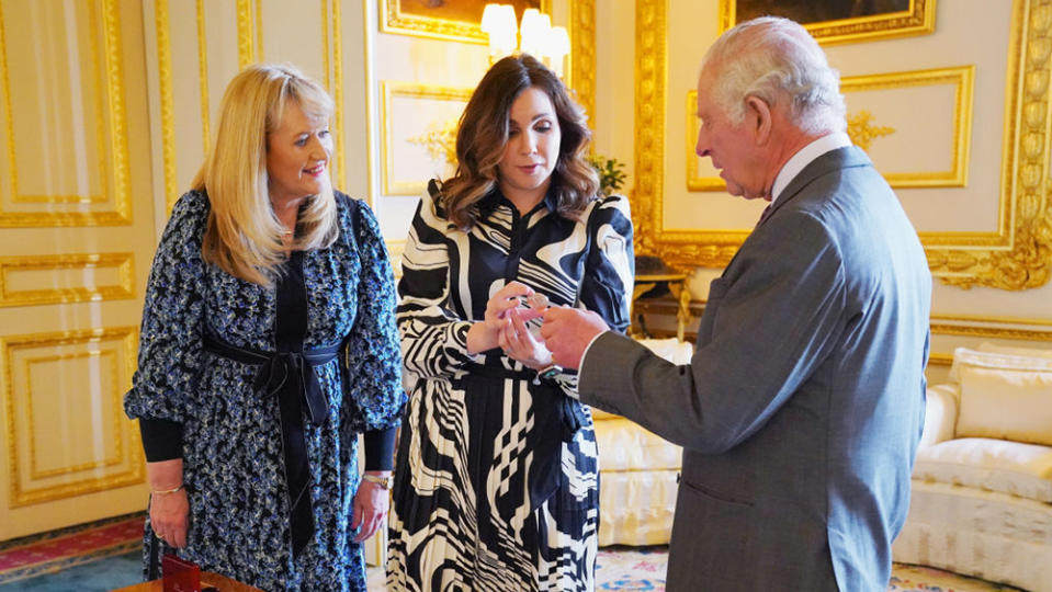 WINDSOR, ENGLAND - APRIL 13: King Charles III is presented with the first struck £5 Coronation coin by Royal Mint CEO Anne Jessopp (left) and Director Rebecca Morgan (centre) on April 13, 2023 at Windsor Castle, Windsor, England.  A crowned portrait of the King will for the first time feature on a new range of commemorative coins created to celebrate the upcoming coronation. The collection, which includes a 50p and £5 coin, will be released later this month ahead of the historic May 6 celebration. (Photo Jonathan Brady - WPA Pool/Getty Images)