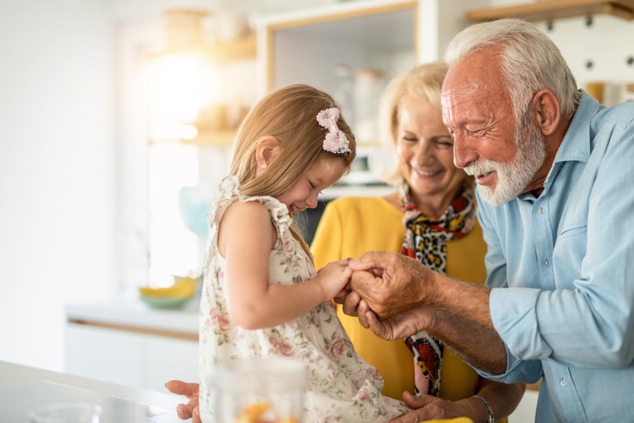 Playful little girl having fun with her grandparents in the kitchen.