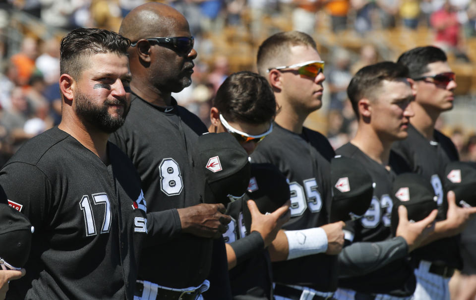 Chicago White Sox first baseman Yonder Alonso (17), first base coach Daryl Boston (8) and other team members stand for the national anthem before a spring training baseball game against the San Francisco Giants, Monday, March 18, 2019, in Glendale, Ariz. (AP Photo/Sue Ogrocki)