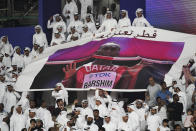 Spectators hold up a poster of high jumper Mutaz Essa Barshim, of Qatar, at the World Athletics Championships in Doha, Qatar, Friday, Oct. 4, 2019. (AP Photo/David J. Phillip)