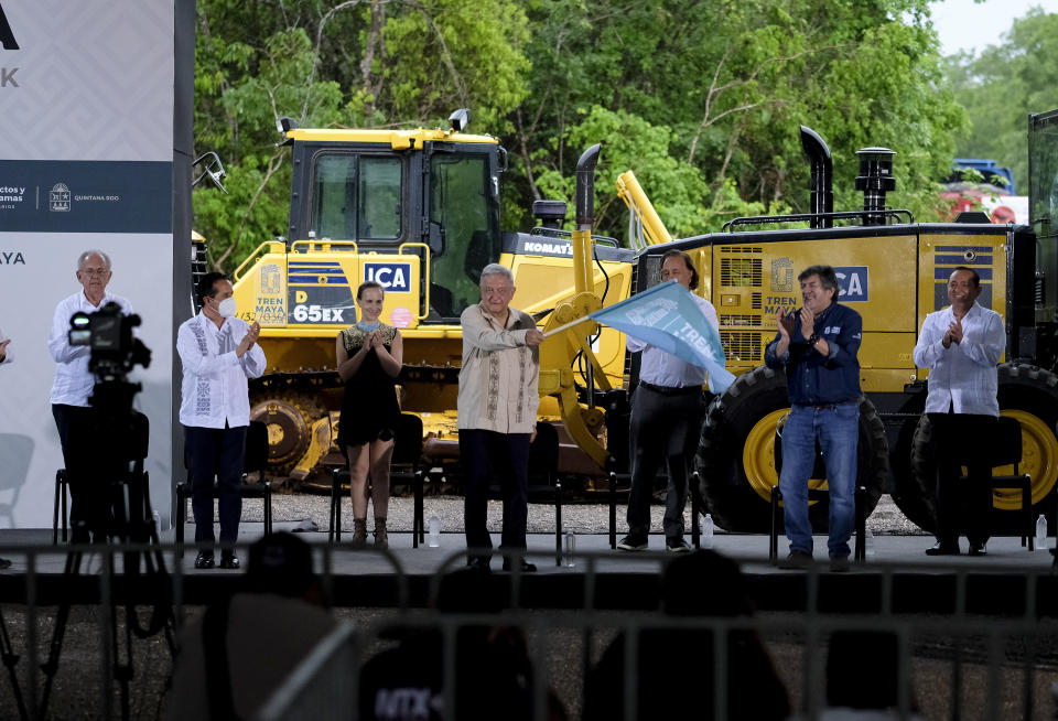 El presidente mexicano Andrés Manuel López Obrador agita una bandera el lunes 1 de junio de 2020 para arrancar las obras del Tren Maya en Lázaro Cárdenas, estado de Quintana Roo. (AP Foto/Víctor Ruiz)