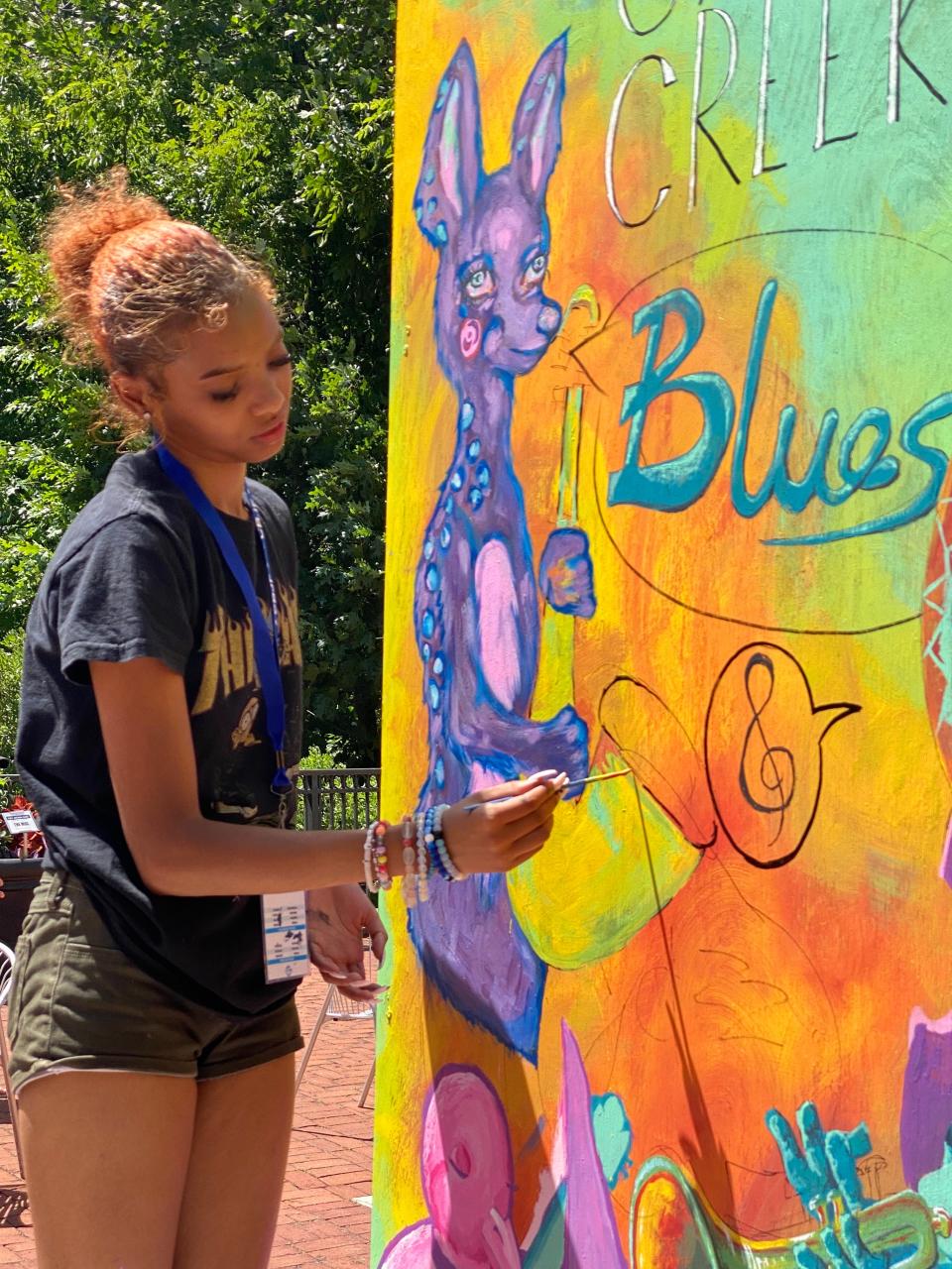 Mya Brooks of Gahanna's Art Love Collective Makers Market, 166 Granville St., works on a whimsical mural featuring the work of several artists.