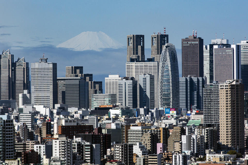 FILE - In this March 29, 2021, file photo, Mount Fuji appears behind the skyline of skyscrapers in the Shinjuku shopping and business district in Tokyo. Business sentiment is growing optimistic, a closely watched economic survey by the Bank of Japan showed Thursday, April 1, 2021, as the world’s third-largest economy continues to grapple with the damage from the coronavirus pandemic. (AP Photo/Kiichiro Sato, File)