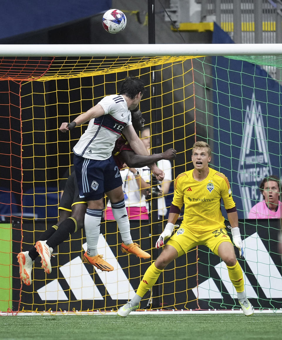 Vancouver Whitecaps' Brian White, front left, gets his head on the ball but puts it over the net behind Seattle Sounders goalkeeper Stefan Cleveland, right, during the first half of an MLS soccer match Saturday, July 8, 2023, in Vancouver, British Columbia. (Darryl Dyck/The Canadian Press via AP)