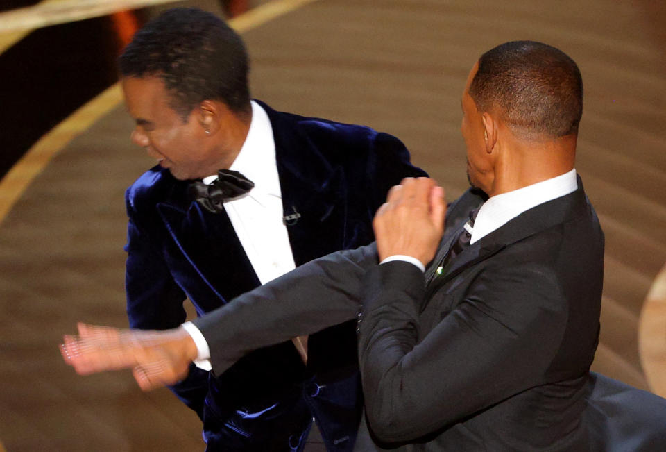 Will Smith (R) hits Chris Rock as Rock spoke on stage during the 94th Academy Awards in Hollywood, Los Angeles, California, U.S., March 27, 2022. REUTERS/Brian Snyder