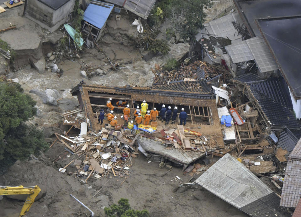 Rescuers work near a house destroyed by a landslide in Karatsu, Saga prefecture, southern Japan Monday, July 10, 2023. Torrential rain has been pounding southwestern Japan, triggering floods and mudslides. (Kyodo News via AP)