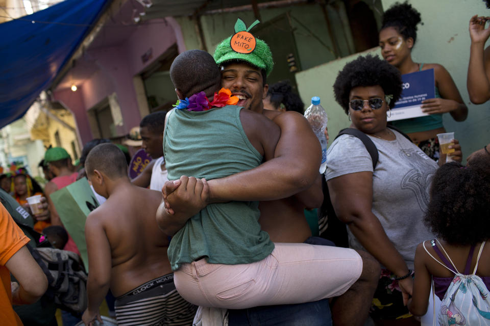 Revelers embrace during the "Se Benze que da" block party, which was created by slain councilwoman Marielle Franco at Mare slum, in Rio de Janeiro, Brazil, Saturday, Feb. 23, 2019. Merrymakers take to the streets in hundreds of open-air "bloco" parties ahead of Rio's over-the-top Carnival, the highlight of the year for many. (AP Photo/Silvia Izquierdo)