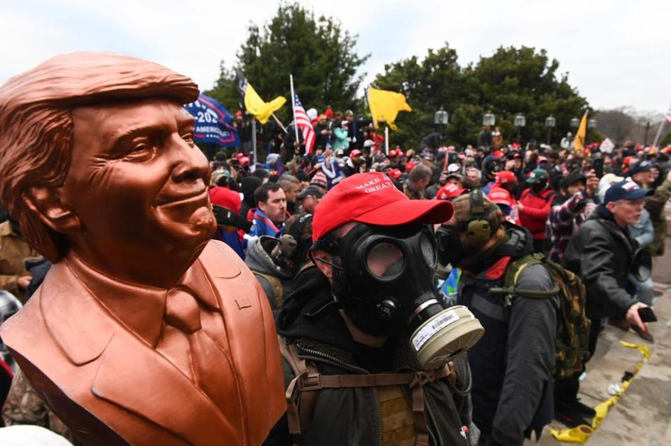 A supporter wears a gas mask and holds a bust of Donald Trump after he and hundreds of others stormed stormed the Capitol building in Washington on 6 January 2021.