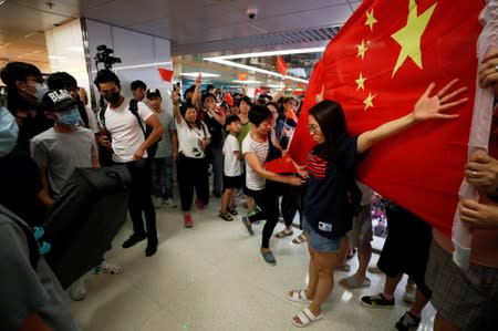 A Pro-China demonstrator stands in front a Chinese national flag during an argument with anti-government protesters at Amoy Plaza shopping mall in Kowloon Bay, Hong Kong