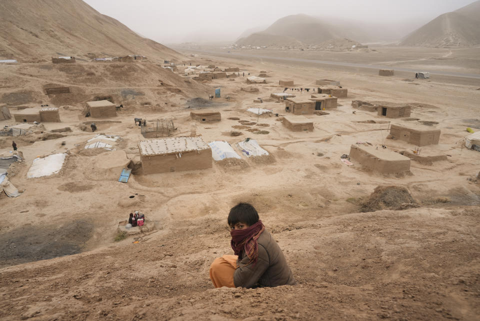 An Afghan boy sits on the hill overlooking the IDP camp near Qala-e-Naw, Afghanistan, Tuesday, Dec. 14, 2021. Severe drought has dramatically worsened the already desperate situation in Afghanistan forcing thousands of people to flee their homes and live in extreme poverty. Experts predict climate change is making such events even more severe and frequent. (AP Photo/Mstyslav Chernov)