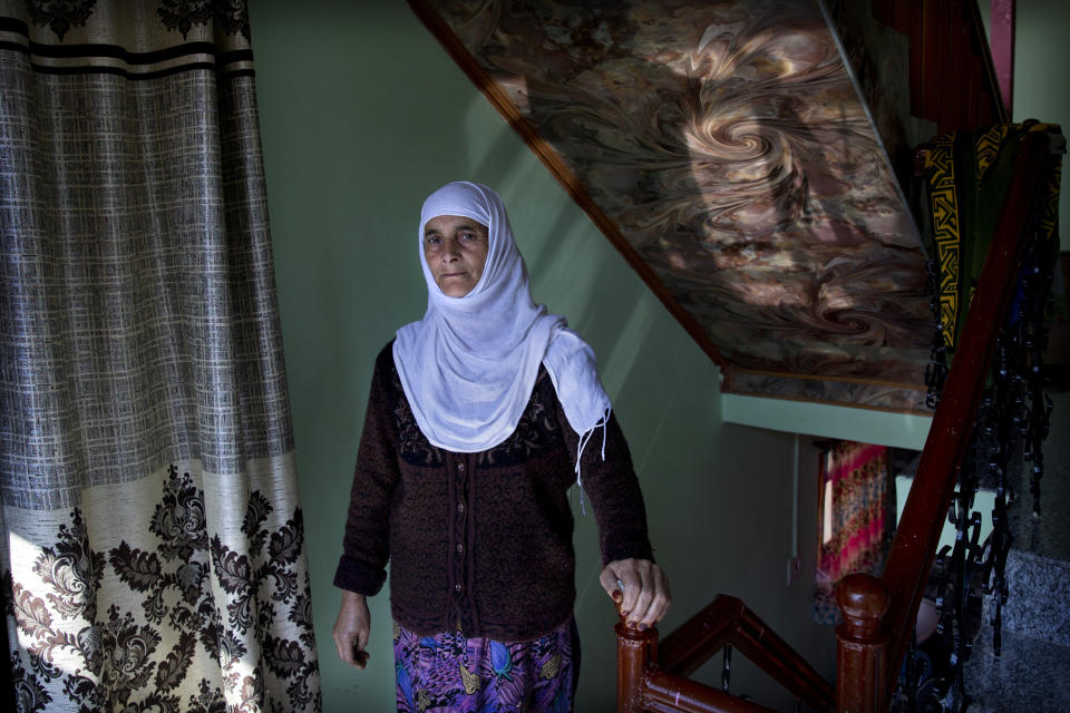 In this Friday, Oct. 14, 2019, photo, a Kashmiri woman Biba Malla stands for a photograph inside her house on the outskirts of Srinagar, Indian-controlled Kashmir. Malla's cousin died on Aug. 31, 2019, but she was informed about it almost a week later. "I missed the funeral and the 'Fateh Khani' condolence meeting, which is held on the fourth day and is very important for us. Our menfolk still haven’t visited fearing detention by police on the way to our relative's home," she said. (AP Photo/ Dar Yasin)