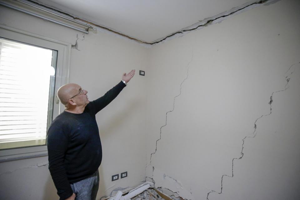 Ilirijan Gaxholli shows the damage to his apartment building in the town of Durres, western Albania, Saturday, Nov 30, 2019. The search and rescue operation for earthquake survivors in Albania has ended, the prime minister said Saturday, with the death toll at 51 and no more bodies believed to be in the ruins. (AP Photo/Visar Kryeziu)