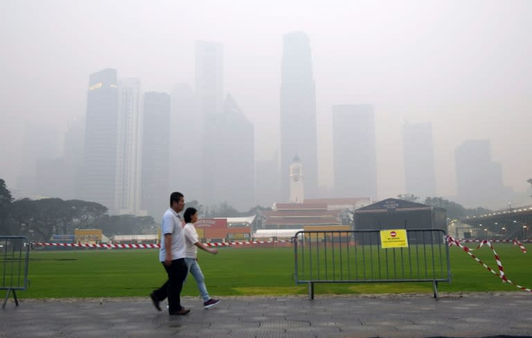 A couple walk before the financial business district shrouded with haze in Singapore on September 14, 201