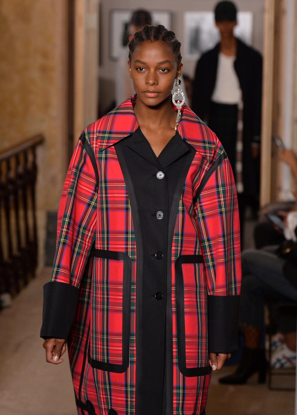 Model wears a crystal chandelier monocle earring and tartan coat from the Burberry September 2017 collection. (Photo: Getty Images)