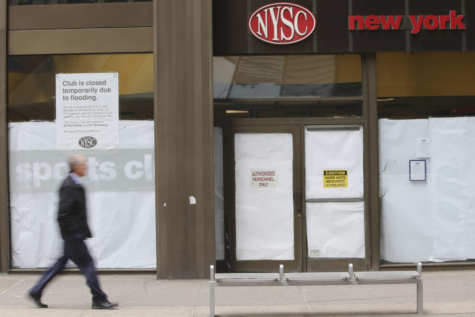 In this Thursday, Feb. 7, 2013 photo, a pedestrian walks past the shuttered New York Sports Club on Water St. in New York. Nearly four months after Superstorm Sandy hit, the historic cobblestone streets near the water's edge in lower Manhattan are eerily deserted, and among local business owners, there is a pervasive sense that their plight has been ignored by the rest of Manhattan. (AP Photo/Mary Altaffer)