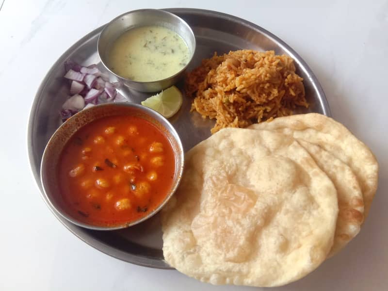 chole bhature, featuring chickpea curry served with fried flatbread and vegetable rice made with potatoes, cauliflower, tomatoes, and peas