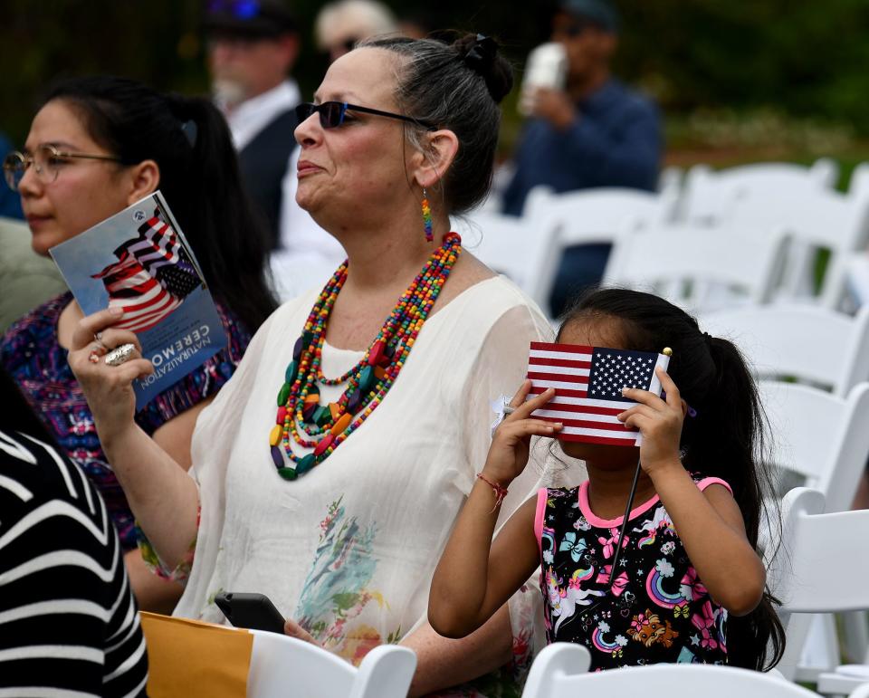 A young girl looks through her American flag as New England Botanic Garden at Tower Hill hosts its second annual naturalization ceremony.