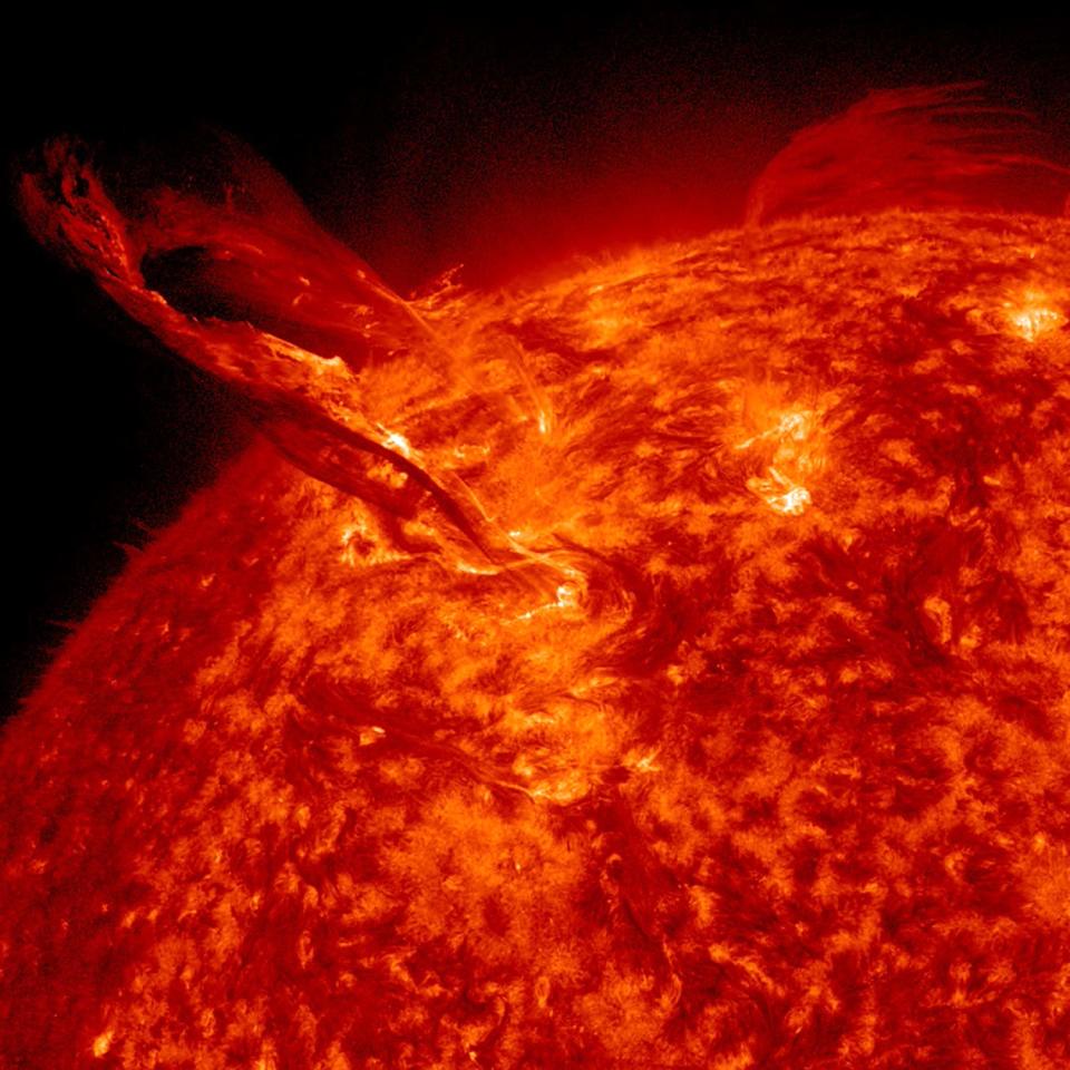 solar flare red-orange plasma erupts from the surface of the sun