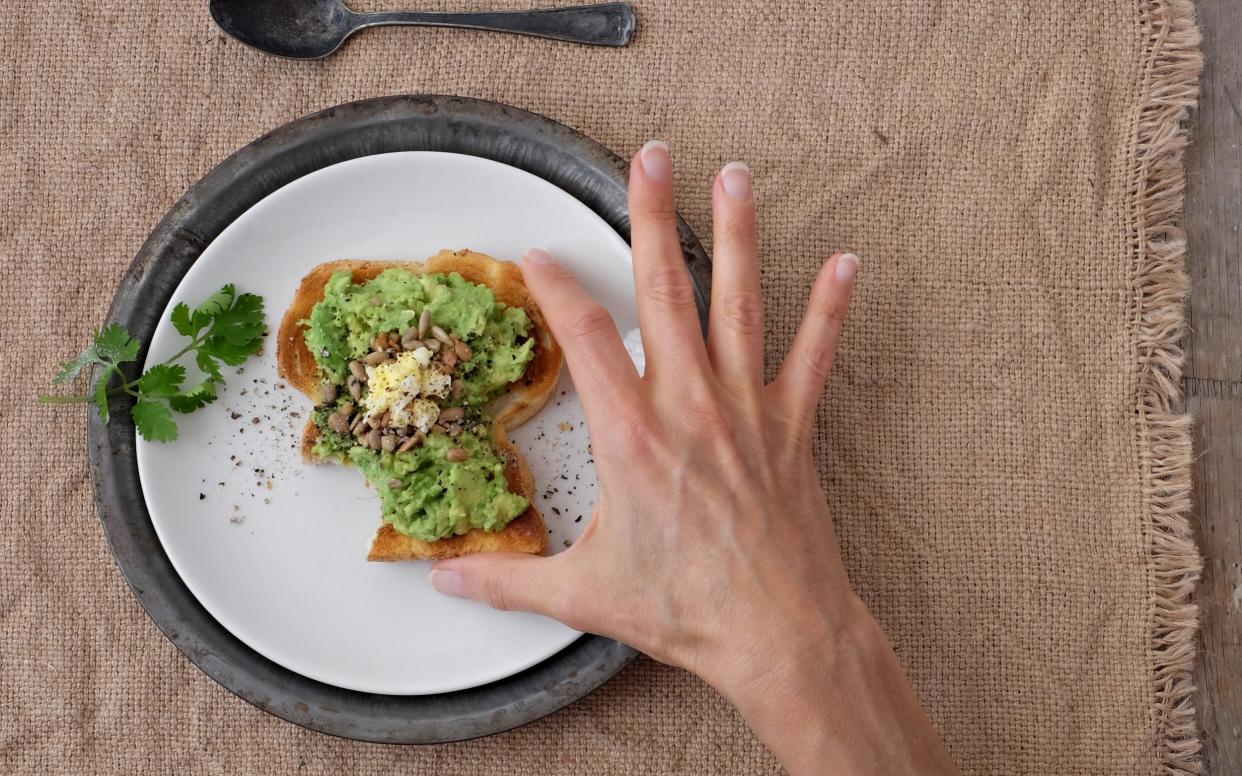 Woman Eating Avocado Toast with Chopped Egg and Sunflower Seeds - Getty Images Contributor