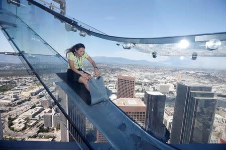 Sandra Brown, 40, rides the Skyslide on the 69th and 70th floors of the U.S. Bank Tower which is attached to the OUE Skyspace LA observation deck in downtown Los Angeles, California, U.S. June 20, 2016. REUTERS/Lucy Nicholson - RTX2H9XM