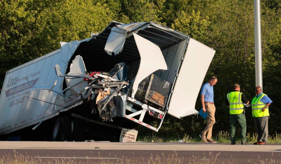 Officials survey a damaged tractor-trailer before removing it from the scene on Wednesday, July 12, 2023, on westbound Interstate 70 after it collided with a Greyhound bus near Highland, Ill. (Christian Gooden/St. Louis Post-Dispatch via AP)