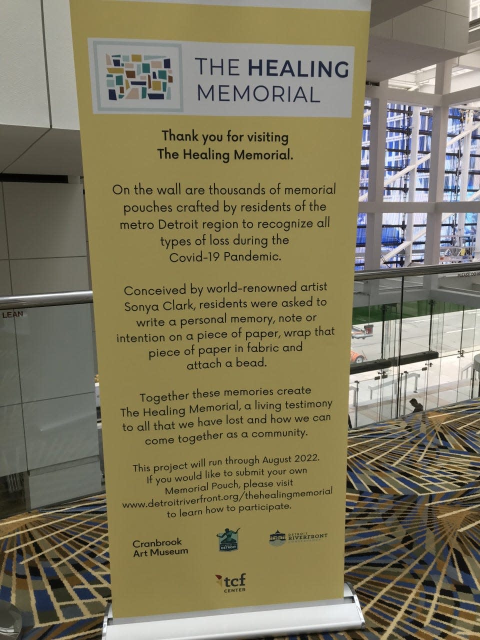 An informational sign about The Healing Memorial, which contains thousands of pouches created by metro Detroiters to recognize loss during the COVID-19 pandemic, in October 2022. The memorial will be moving from inside Huntington Place in downtown Detroit to the Cranbrook Art Museum in Bloomfield Hills.