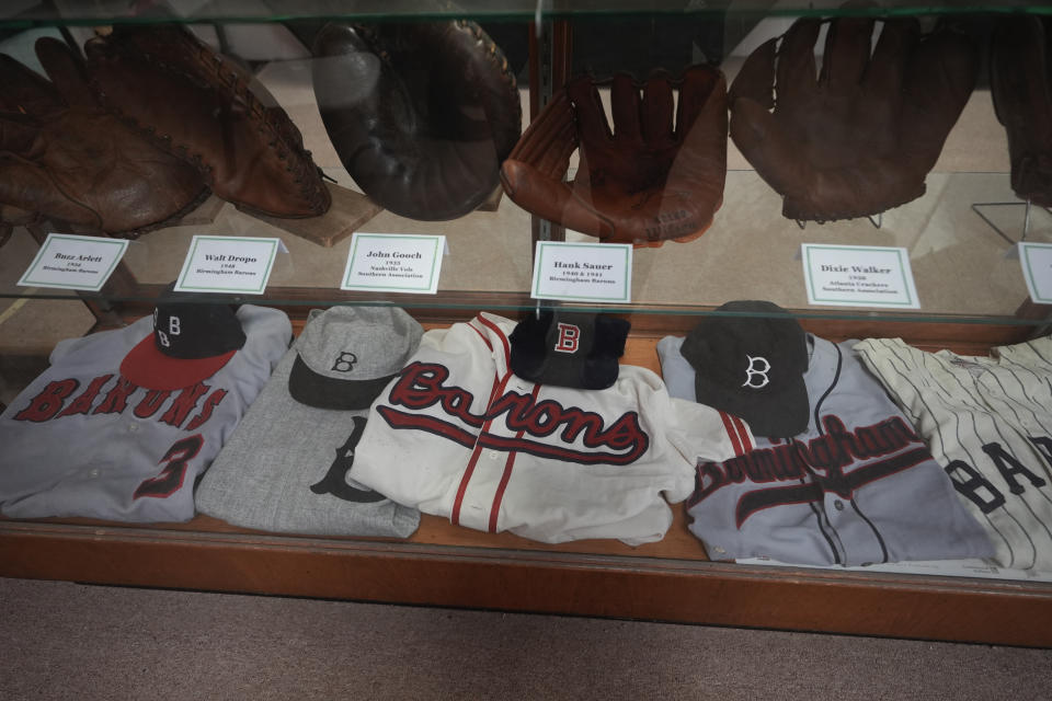 Former uniforms of the Birmingham Barons baseball team and gloves are on display in a shop near Rickwood Field, Monday, June 10, 2024, in Birmingham, Ala. Rickwood Field, known as one of the oldest professional ballpark in the United States and former home of the Birmingham Black Barons of the Negro Leagues, will be the site of a special regular season game between the St. Louis Cardinals and San Francisco Giants on June 20, 2024. (AP Photo/Brynn Anderson)