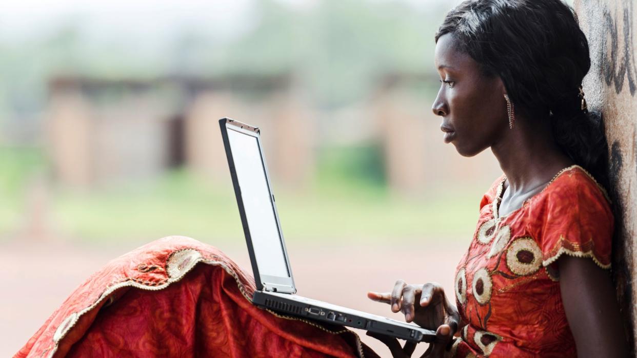  Street Shot of an African Ethnicity young woman working on business holding her technology item computer in a university in Bamako, Mali. . 