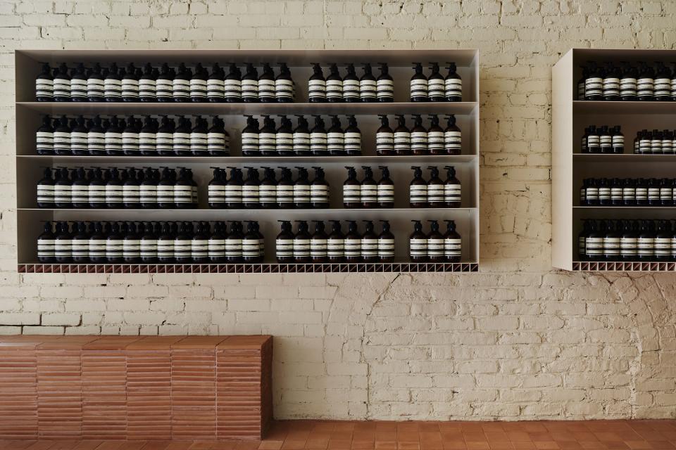 Minimal white shelving and exposed-brick walls create visual contrast with the earth-toned tiles.