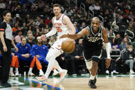 Milwaukee Bucks' Khris Middleton (22) attempts to save the ball from going out of bounds in front of New York Knicks' Isaiah Hartenstein (55) during the first half of an NBA basketball game Sunday, April 7, 2024, in Milwaukee. (AP Photo/Aaron Gash)