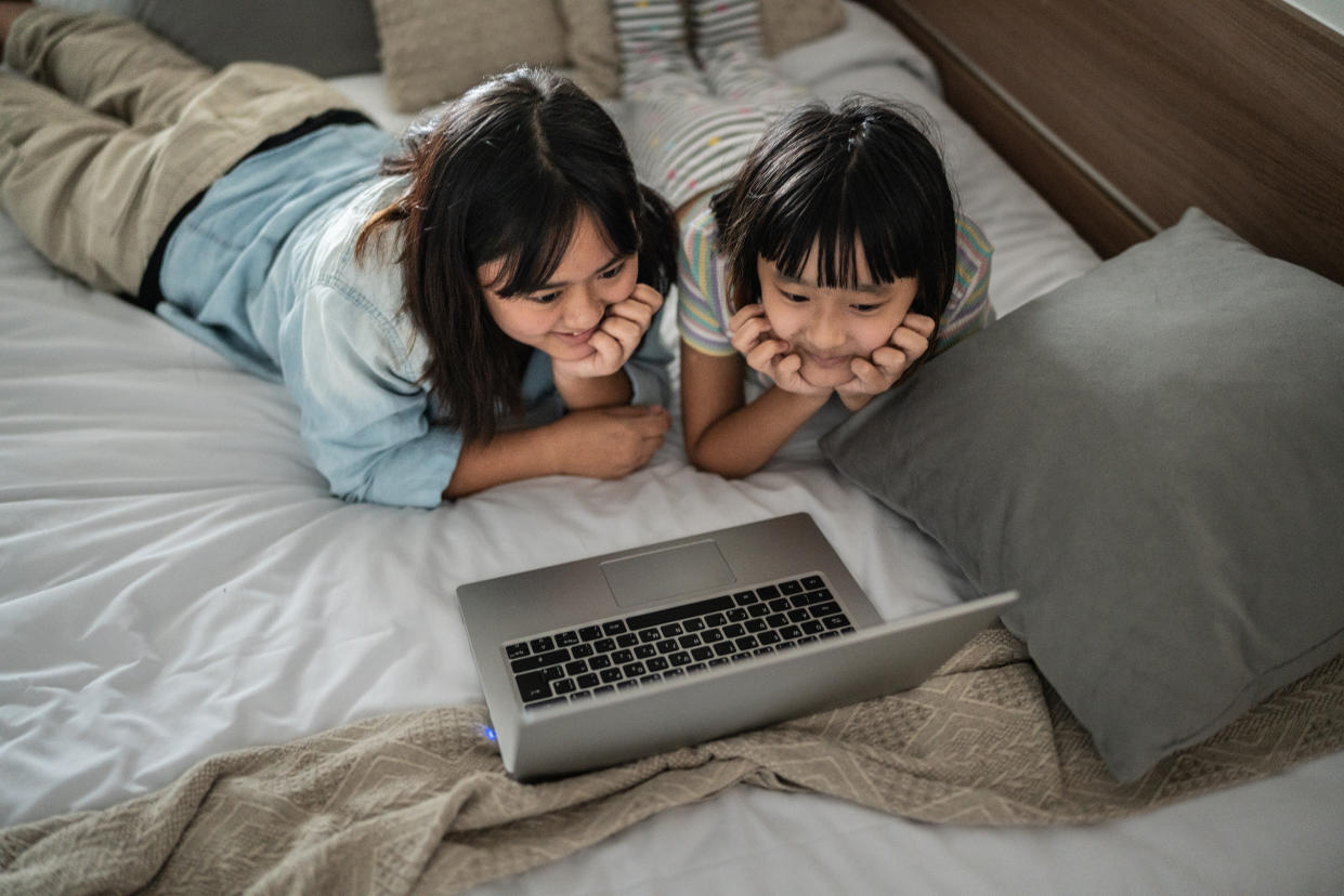 Girls watching a movie on the laptop in bed at home