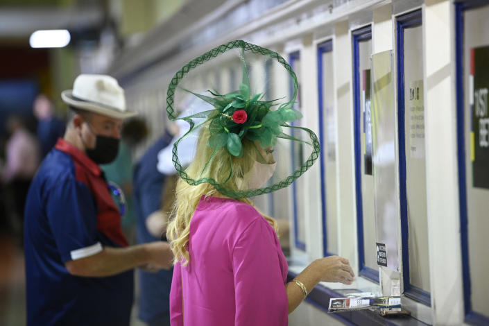 A woman wears a hat while placing a bet during the Preakness Stakes horse race at Pimlico Race Course, Saturday, May 15, 2021, in Baltimore. (AP Photo/Nick Wass)