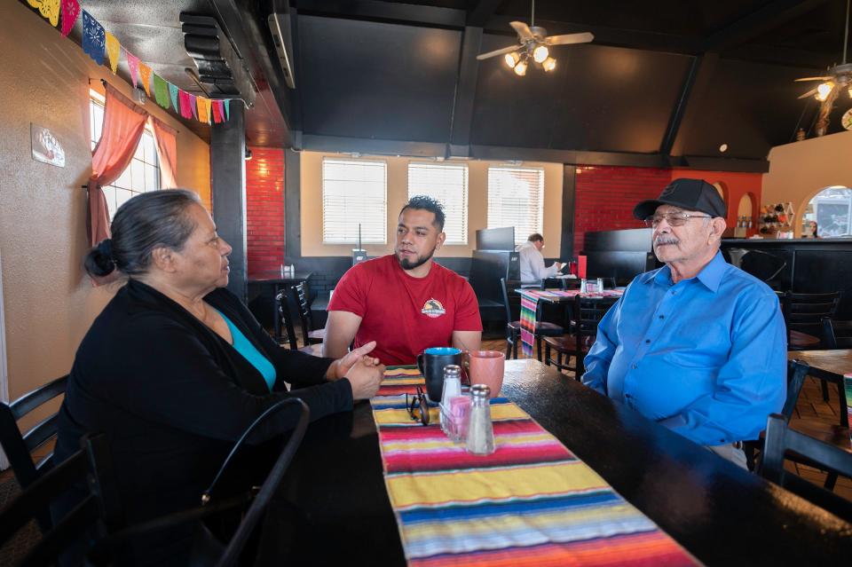 Jess Rojas, center, has a conversation with his parents Rosario Rojas and Jose Victor Rojas Sr., right, in the dining area of the new Garlic & Onions To Go restaurant on Friday, March 31, 2023.