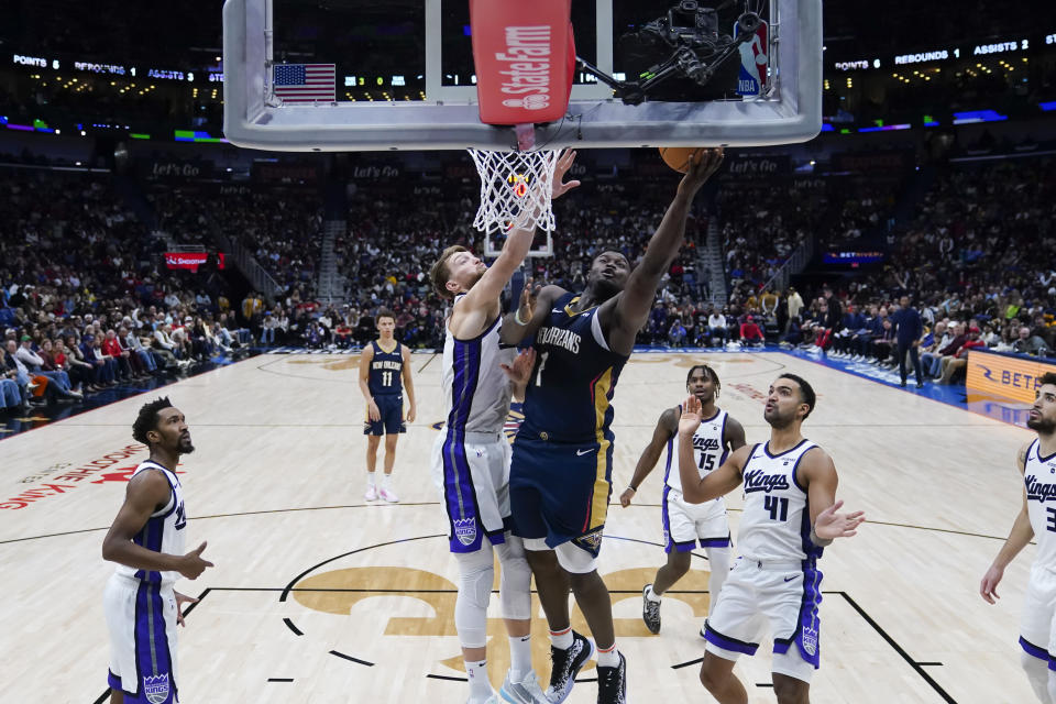 New Orleans Pelicans forward Zion Williamson (1) drives to the basket against Sacramento Kings forward Domantas Sabonis (10) and forward Trey Lyles (41) in the second half of an NBA basketball game in New Orleans, Wednesday, Nov. 22, 2023. The Pelicans won 117-112. (AP Photo/Gerald Herbert)