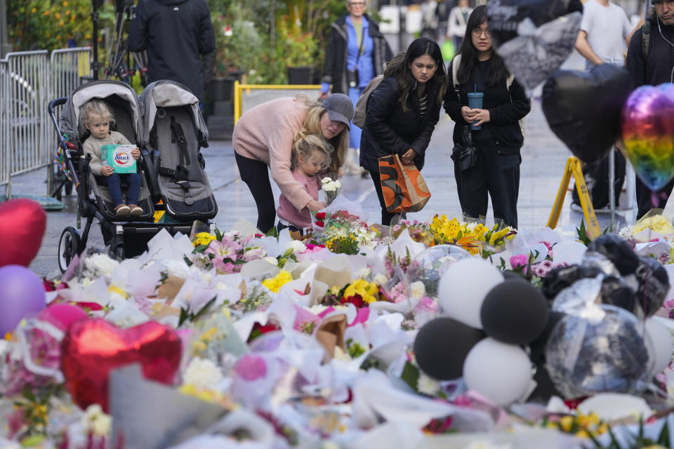 People lay flowers at a tribute for the victims in Saturday's knife attack near a crime scene at Bondi Junction in Sydney, Thursday, April 18, 2024. A Sydney shopping mall has been opened to the public for the first time since it became the scene of a mass stabbing in which six people died, while the Australian prime minister has flagged giving citizenship to an immigrant security guard who was injured while confronting the knife-wielding attacker. (AP Photo/Mark Baker)