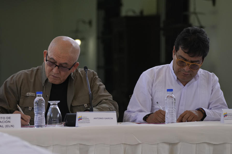 Antonio Garcia, of the Colombian guerrilla National Liberation Army (ELN), left, and Colombian government representative Ivan Danilo Rueda sign an agreement to resume peace talks, at the Casa Cultural Aquiles Nazoa in Caracas, Venezuela, Tuesday, Oct. 4, 2022. The agreement comes after more than four years of suspension, and will start in November. (AP Photo/Ariana Cubillos)