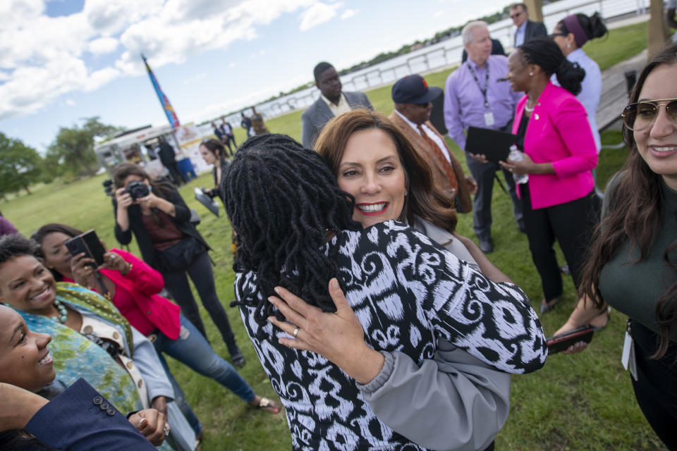 Michigan Gov. Gretchen Whitmer, right, gets a hug from district court judge Jacquelyn McClinton before a press conference on Belle Isle, in Detroit, on Tuesday, June 22, 2021, announcing the end of COVID restrictions in the state. After facing 15 months of capacity restrictions and being hit by the country’s worst surge of coronavirus infections this spring, restaurants, entertainment businesses and other venues can operate at 100% occupancy starting Tuesday. (David Guralnick/Detroit News via AP)